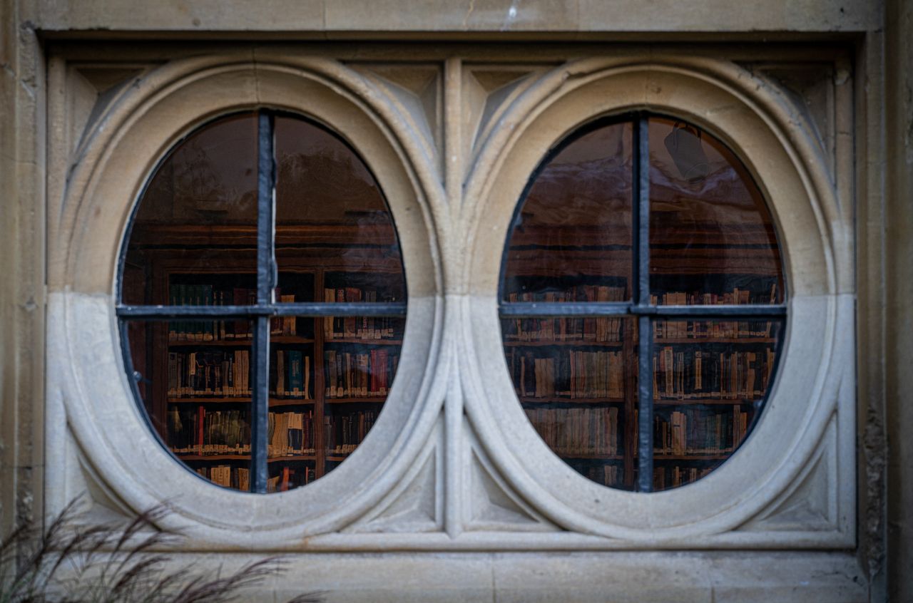 Reflection of a library through a double arched window in Oxford, UK.